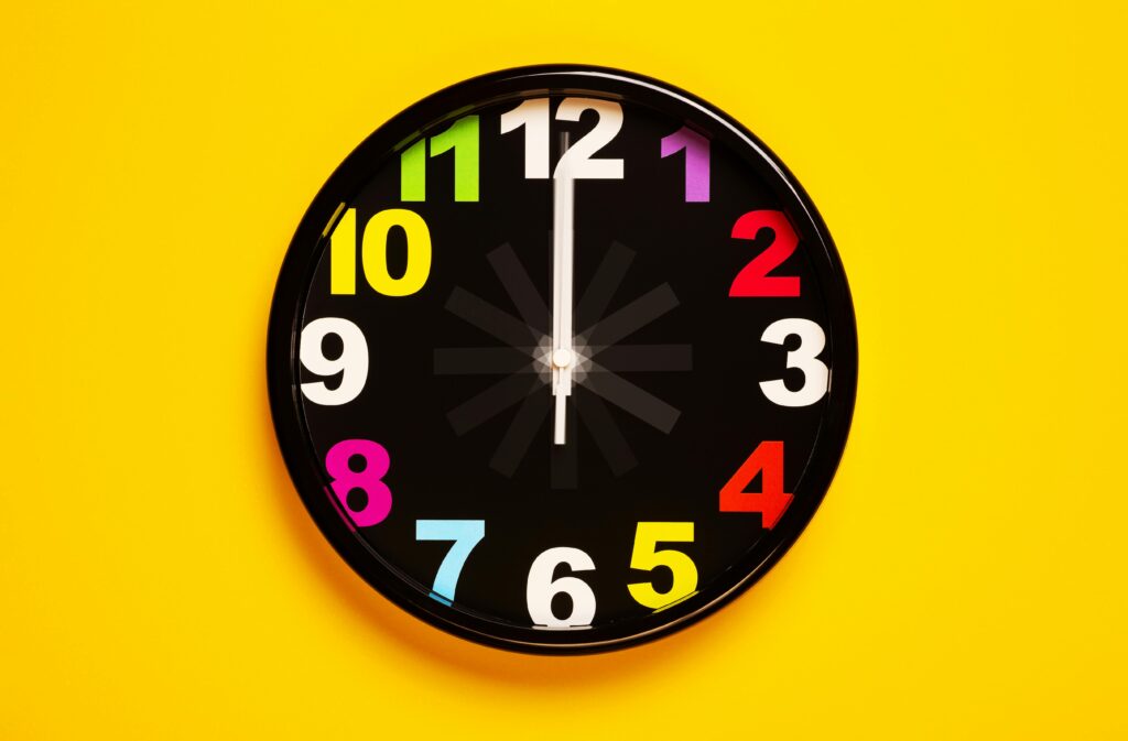 Vibrant wall clock with colorful numbers on a bright yellow background, emphasizing modern decor.